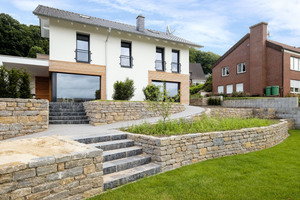  Das Einfamilienhaus präsentiert sich mit einem elegant gestalteten Übergang zum terrassierten Garten. 