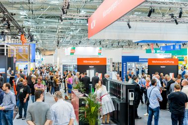 Viele Menschen gehen in der Messehalle umher, ?berall sind Messest?nde.