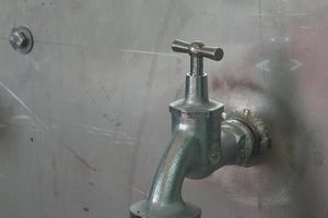  Kennzeichnung einer Entnahmestelle nach Vorgaben der DIN EN 16941-1, um Verwechslungen mit Trinkwasser durch die Nutzer zu verhindern. Dieses Ventil ist an einem großen Waschbecken installiert, das zur Reinigung von Bauteilen in der Produktionshalle dient. 