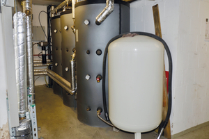  Im gleichen Raum um die Ecke befinden sich die drei Pufferspeicher sowie der wandhängende unterstützende Gasbrennwertkessel, hier von den Nahwärmeleitungen verdeckt. 